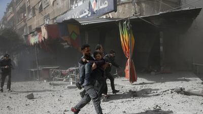 A man runs as he holds a girl after an air strike on Douma on February 7, 2018. Bassam Khabieh / Reuters