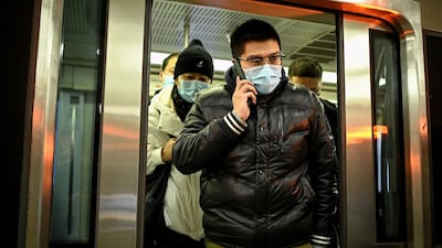 A man wearing a face mask uses his mobile phone as he exits a subway train in Beijing on December 17, 2020. AFP