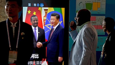 African delegates walk by a screen showing a footage of Xi Jinping with Ethiopia's Prime Minister. AP