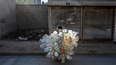 An Afghan boy carrying empty plastic containers walks along a street in Kabul. AFP