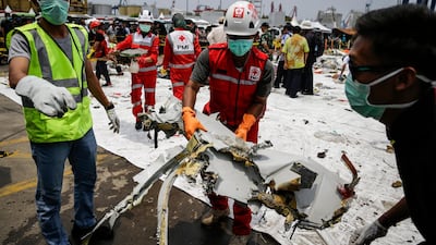 Indonesian rescuers sort through plane debris at port.