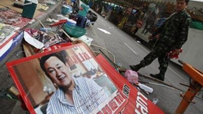 A Thai soldier walks by a poster of ousted Prime Minister Thaksin Shinawatra left behind by anti-government protesters Friday, May 21, 2010, in Bangkok, Thailand.