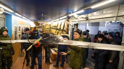 Visitors and journalists look at weapons and drones on display. AP Photo
