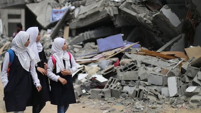 Palestinian students look at a building that was destroyed by Israeli air strikes near their damaged school in Gaza City May 7, 2019. Reuters