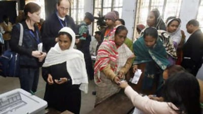 European Union election observation officials watch Bangladeshi voters prepare to cast their votes at a polling station in Dhaka.