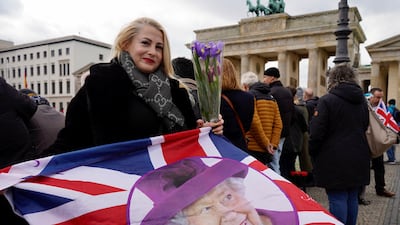 Ewa from Berlin holds a Union Jack flag with a picture of the late Queen Elizabeth II before the welcome ceremony for King Charles. Reuters