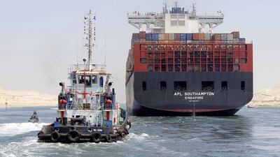 A container ship is guided by boats as it crosses the new waterway of the Suez canal on Saturday, July 25. AFP