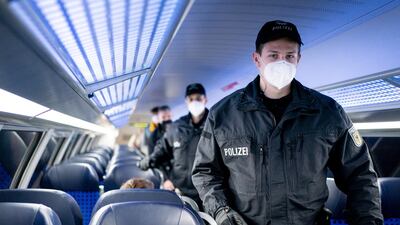 Federal police officers patrols a regional train in Berlin checking passengers are wearing masks. AP