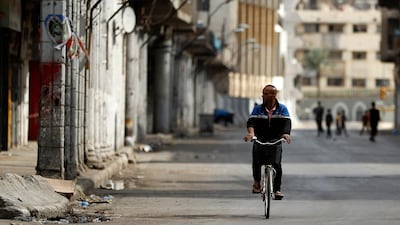 A man cycles past shops that were shut to curb the spread of the coronavirus in Baghdad, Iraq. AP