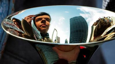 A cast member looks at his reflection in a trombone while the cast of Broadway show 'The Music Man' pose for photos in New York. Reuters