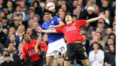 Everton's Marouane Fellaini, center, and Manchester United's Nemanja Vidic, right, battle for the ball during the English Premier League soccer match at Goodison Park, Liverpool, England.