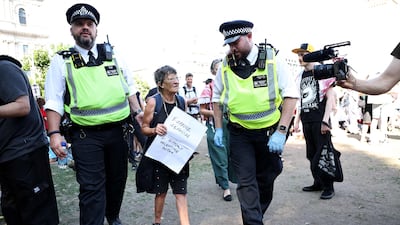 A protester is led away by police officers at a "Lift The Ban" demonstration in support of the proscribed group Palestine Action, calling for the recently imposed ban to be lifted, in Parliament Square, central London, on August 9, 2025. Organisers expect at least 500 people to turn up to a new demonstration in support of Palestine Action today, and police have warned all demonstrators could face arrest. Palestine Action was proscribed under the 2000 Terrorism Act. (Photo by HENRY NICHOLLS / AFP)