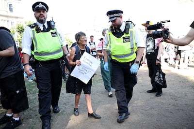A protester is led away by police officers at a 'Lift The Ban' demonstration in Parliament Square, central London. AFP