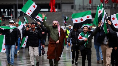 Supporters of Mr Al Shara wave Syrian flags as they gather in the German capital. Reuters