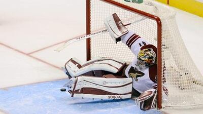 Phoenix goalkeeper Mike Smith falls back into the net after blocking a shot from San Jose Sharks.