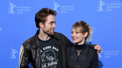 In a black leather jacket, logo T-shirt and yellow trousers, Robert Pattinson poses with Mia Wasikowska at the 'Damsel' photocall in Berlin on February 16, 2018. Getty Images