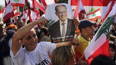 A Lebanese woman holds a picture of Lebanon's newly elected president, Michel Aoun, at the presidential palace in Baabda. Bilal Hussein / AP Photo