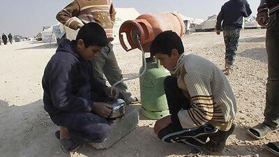 Syrian refugee boys fill cooking gas cylinders at the Al Zaatari refugee camp in the Jordanian city of Mafraq, near the Syrian border, where it is now almost impossible to obtain gas.