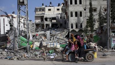 Palestinians flee their home in northern Gaza as they pass by a home that was recently damaged by an Israeli air strike as they travel to take shelter at the United Nations school in Gaza City, Sunday, July 13, 2014. Israel briefly deployed ground troops inside the Gaza Strip for the first time early Sunday as its military warned northern residents to evacuate their homes, part of a widening campaign against militant rocket fire that's seen more than 160 Palestinians killed. (Photo by Heidi Levine for The National).