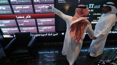 Investors talk as they monitor screens displaying stock information at the Saudi stock exchange in Riyadh. Reuters