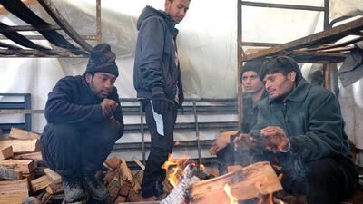 Migrants warm themselves around a fire. A fresh spate of snowy and very cold winter weather has brought more misery for hundreds of migrants. AP Photo