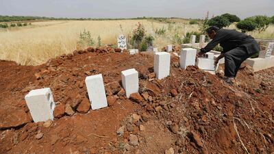 A man puts stones on the graves of five victims of a regime air strike on the village of Kafr Aweid in Idlib. AFP/Omar Haj Kadour