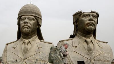 American army soldiers stroll past two bronze busts of former Iraqi president Saddam Hussein in the Green Zone in Baghdad. Hadi Mizban / AP Photo