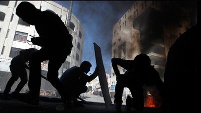 Hiding in the shadows: Palestinian protesters take cover during clashes with Israeli soldiers in the West Bank city of Hebron. Ammar Awad / Reuters