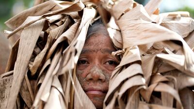 A devout Catholic, covered in mud and dressed in dried banana leaves, participates in mass