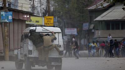 Policemen take cover behind a vehicle as Kashmiri protesters throw stones and bricks at them during a protest in Srinagar. Dar Yasin / AP Photo