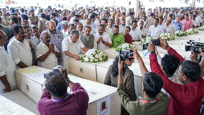 Mr Vijayan lays a wreath on a coffin. AFP