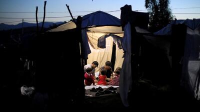 Two migrant men and four babies sit inside a tent at a makeshift camp next to the Moria camp for refugees and migrants on the island of Lesbos, Greece. Reuters