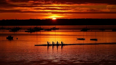 Rowers begin their workout on Casco Bay as the sun starts to peak over Great Diamond Island in Portland, Maine. AP