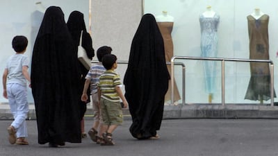 Saudi women with their children pass by a women's boutique in Jeddah. AFP