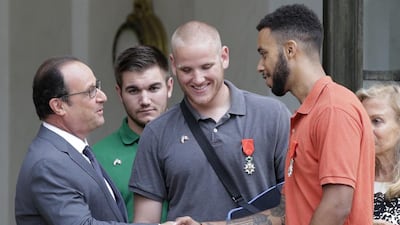 Francois Hollande, the France president, left, shakes hands with American student Anthony Sadler, right, with US servicemen Spencer Stone, centre right, Alek Skarlatos, centre left, looking on. The Americans and a Briton were awarded France's top honour for thwarting a terror attack on a train. Philippe Wojazer / Reuters