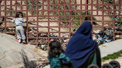 A child plays while a woman sits with another infant on the ground at Camp Roj. AFP