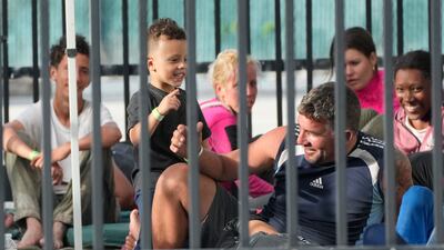 A young boy plays with recently arrived migrants. AP