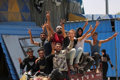 Men gesture with the V-for-victory sign as they ride on the back of tricycle away from Deir El Balah in the central Gaza Strip after an eviction order by the Israeli army. AFP