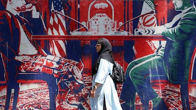 An Iranian woman walks past an anti-US mural (depicting an Iranian and US negotiation table) next to the former US embassy in Tehran, Iran, 22 June 2026. Leaders of the Iranian negotiation team, Mohammad Bagher Ghalibaf and Abbas Araghchi, left the Lucerne Summit in Switzerland after 18 hours of talks with the US, Pakistan, and Qatar. EPA/ABEDIN TAHERKENAREH RESTRICTIONS: NO Access Israel Media/Persian Language TV Stations Outside Iran/Strictly No Access BBC Persian/VOA Persian/Manoto TV/Iran International TV. (As mandated by Iran's Directorate General for Foreign Media) --