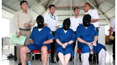 Indonesian officers stand behind three drug smuggling suspects from Iran, France and Indonesia during a press conference in Jakarta this week.