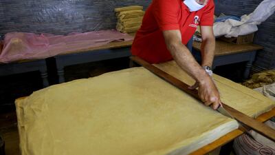 A worker cuts the dough of pastry sheets of sambusa snacks during the holy month of Ramadan in Sanaa, Yemen April 16, 2021. Reuters
