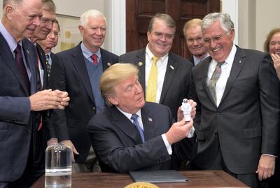 US President Donald Trump holds up an astronaut toy alongside former US Senator and Apollo 17 Astronaut Jack Schmitt (R), after a signing ceremony for Space Policy Directive-1, with the aim of returning Americans to the moon. AFP PHOTO