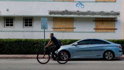 A man rides a bike by a building with boarded up windows during a hurricane alert in South Miami Beach, Florida. AFP