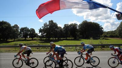A French flag flies over riders during Stage 12. AP