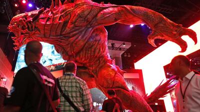People walk past a statue of a game character at the Take Two booth during the 2014 Electronic Entertainment Expo, known as E3, in Los Angeles, California June 11, 2014. Reuters