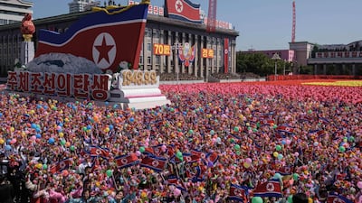 Participants wave flowers as they march past a balcony from where North Korea's leader Kim Jong Un was watching, during a mass rally on Kim Il Sung square in Pyongyang. AFP