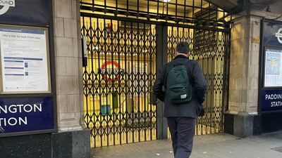 Commuters walk by a closed Paddington underground station. PA