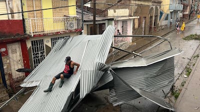 A resident of Santiago in Cuba slides down part of the roof of his house, damaged by Hurricane Melissa. AFP