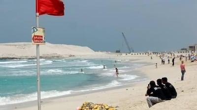 A red flag indicates dangerous currents for swimmers at a beach near the Burj al Arab.