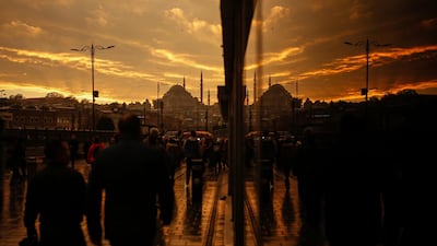 Backdropped by the iconic Suleymaniye Mosque in Istanbul, people are reflected in a glass as they walk on a bridge over the Golden Horn. AP Photo